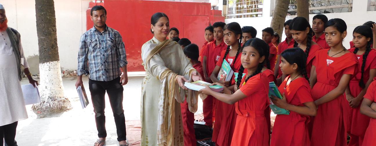 শিক্ষার্থীদের হাতে নতুন বছরের বই তুলে দিচ্ছেন ।
